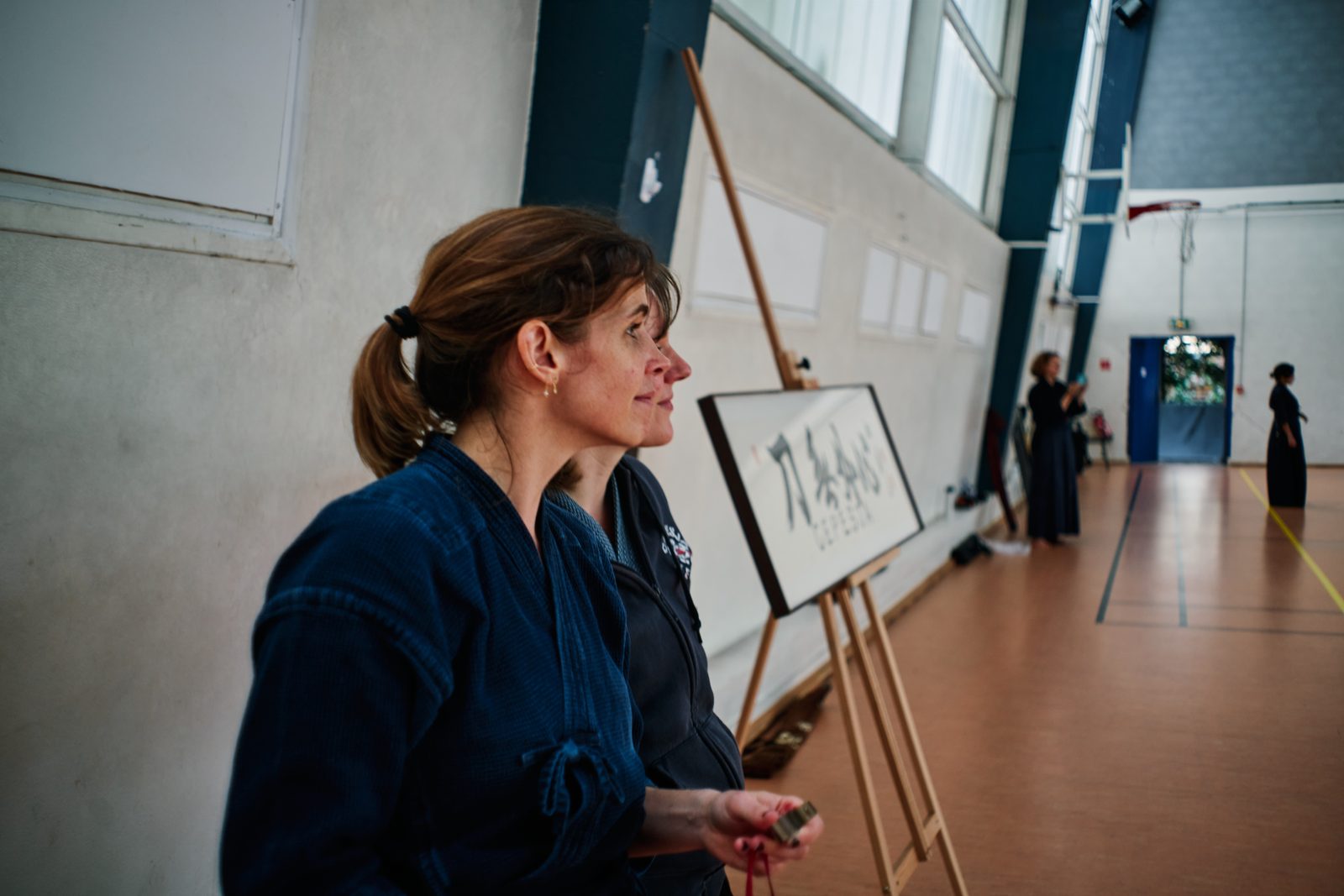 Pratiquante du CEPESJA devant la calligraphie du dojo